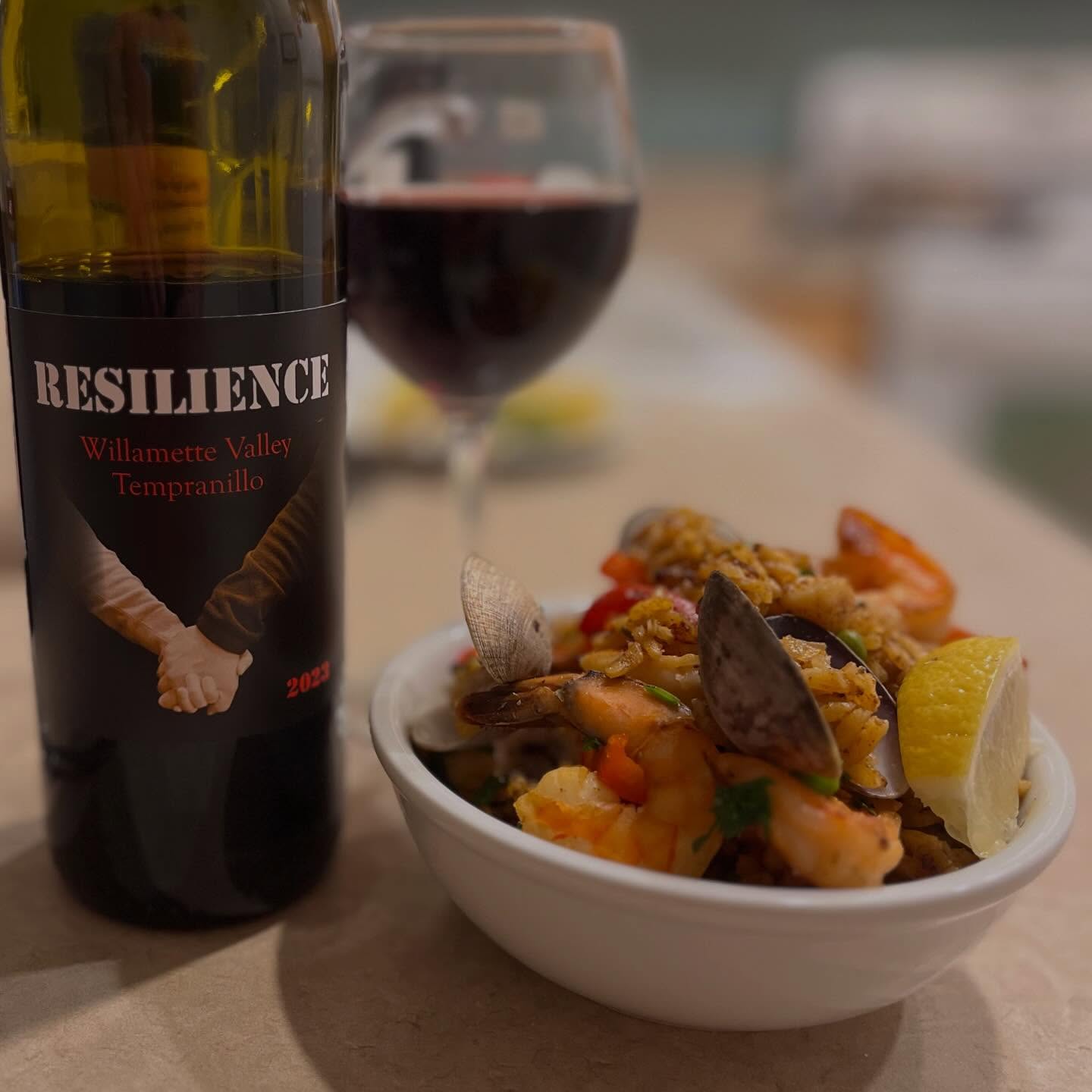 resilience tempranillo in a glass with a bowl of paella